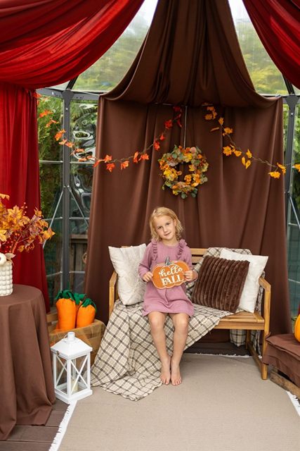 Dziewczynka na drewnianej ławce z poduszką „hello fall”