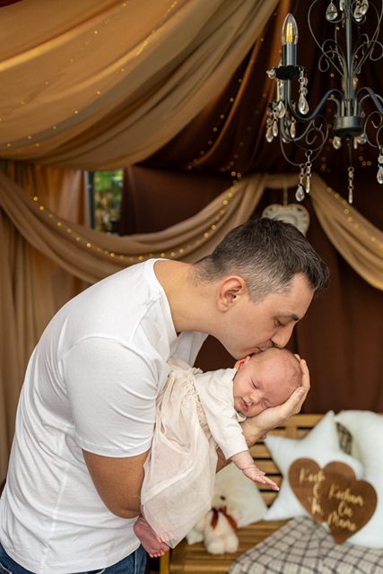 Tata tuli i całuje w główkę śpiące niemowlę