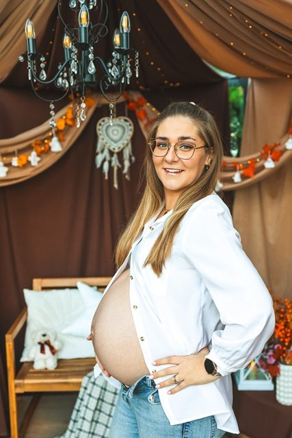 Kobieta w ciąży bokiem, w jesiennej scenerii szklarni