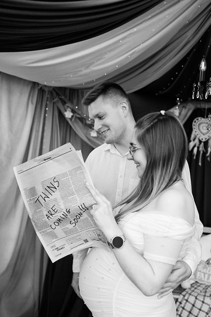 Czarno-biały kadr pary z gazetą „Twins are coming soon”
