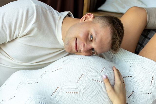 Mężczyzna opiera głowę na brzuszku partnerki